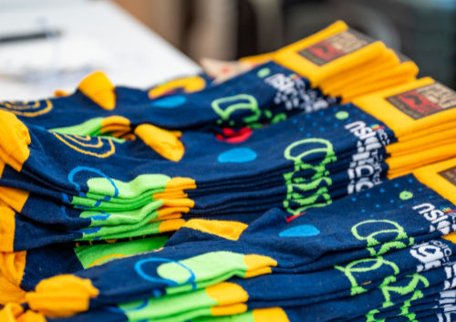 Colorful socks with abstract patterns and yellow cuffs displayed in a stack on a table